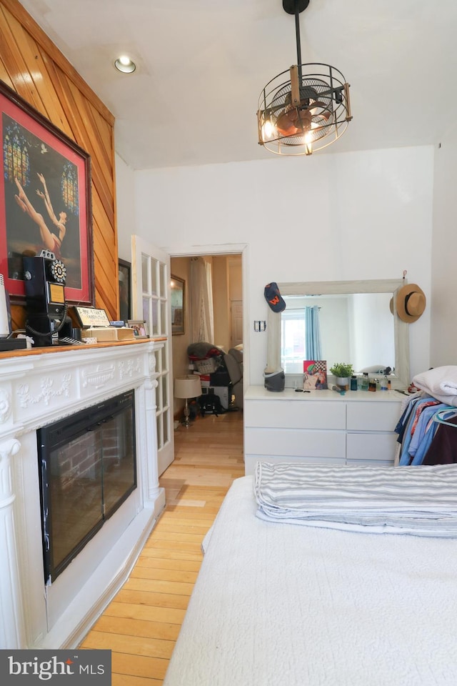 bedroom with a glass covered fireplace, light wood-style flooring, and recessed lighting