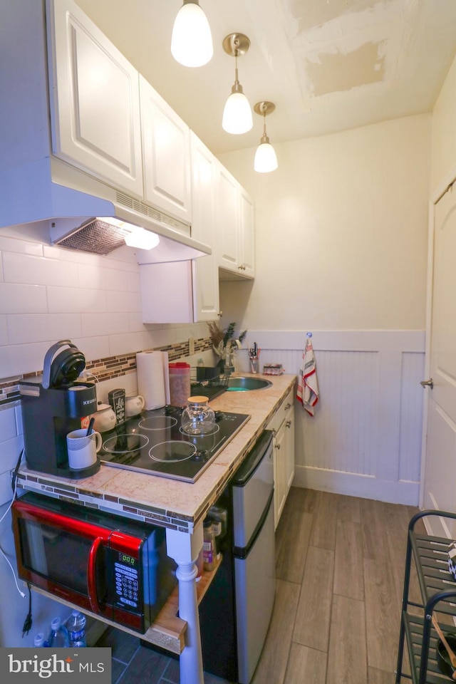 kitchen with light wood-style flooring, white cabinets, dishwasher, and wainscoting