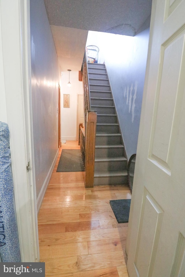 staircase featuring baseboards and wood finished floors