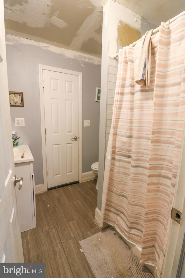 full bath with baseboards, vanity, toilet, and wood finished floors