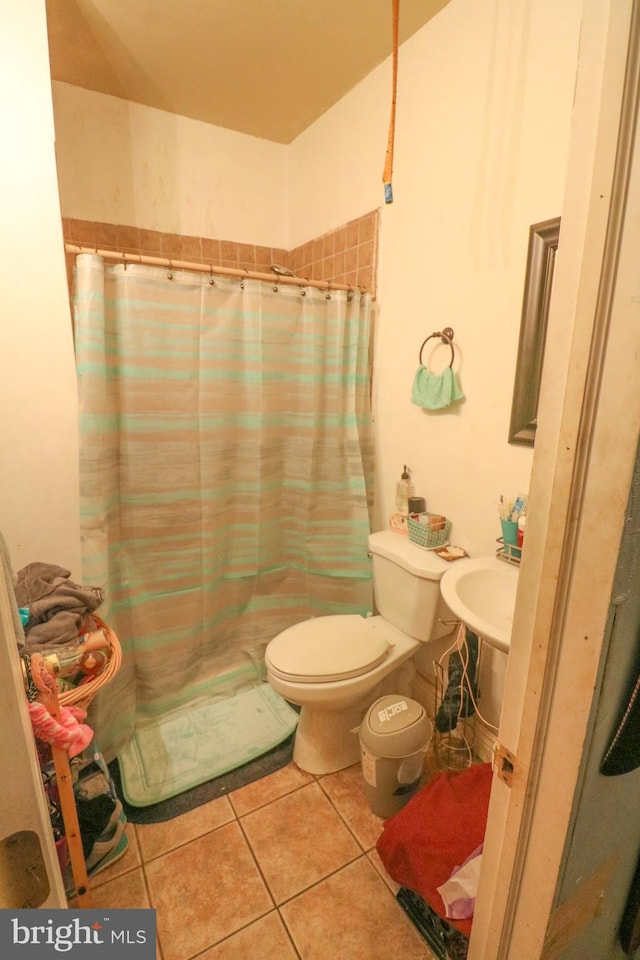 bathroom with a shower with curtain, a sink, and tile patterned floors