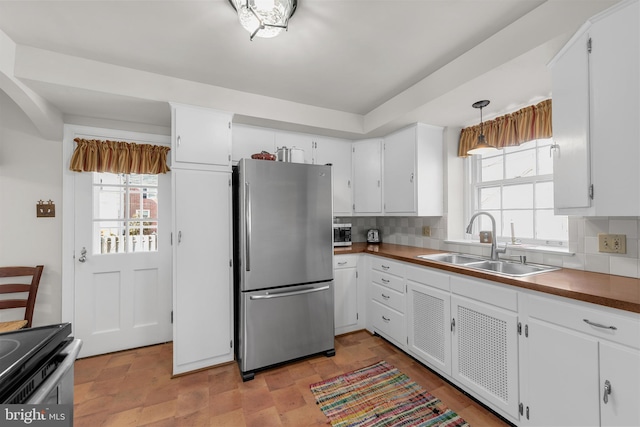 kitchen featuring white cabinetry, backsplash, a sink, and freestanding refrigerator