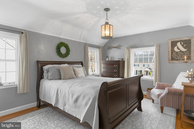 bedroom with lofted ceiling, multiple windows, wood finished floors, and baseboards