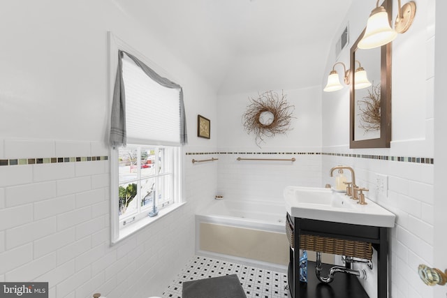 full bathroom with lofted ceiling, a garden tub, tile walls, wainscoting, and tile patterned floors