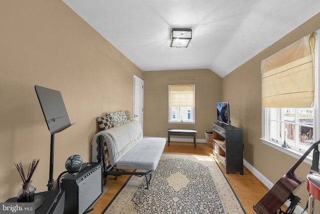 sitting room with lofted ceiling, light wood finished floors, baseboards, and a wealth of natural light