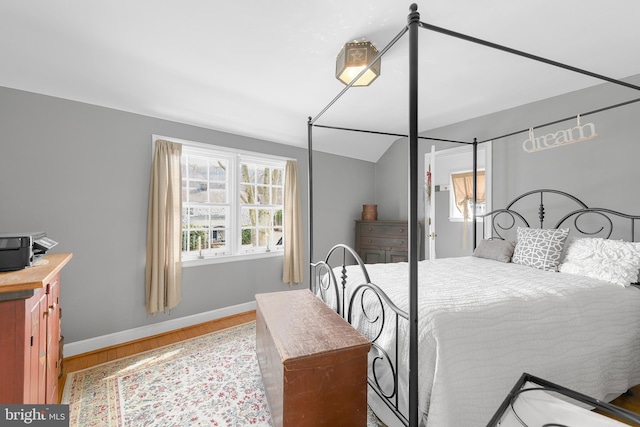 bedroom with lofted ceiling, baseboards, and wood finished floors