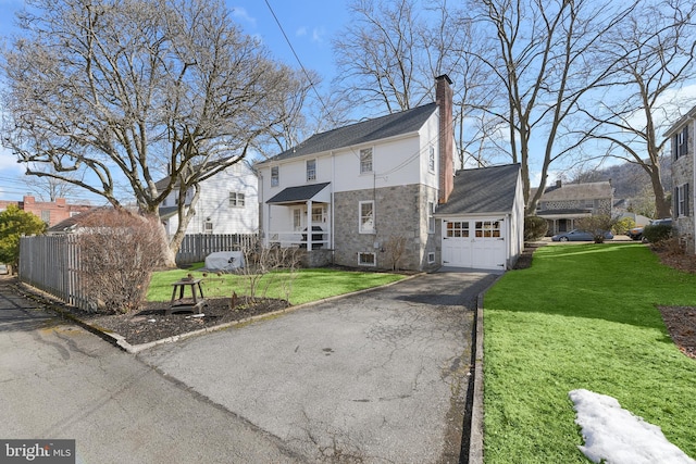 view of front of property featuring aphalt driveway, a front lawn, an attached garage, and fence