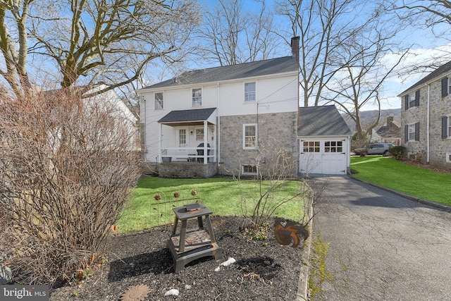 view of front of property featuring a front yard, driveway, a chimney, and an attached garage