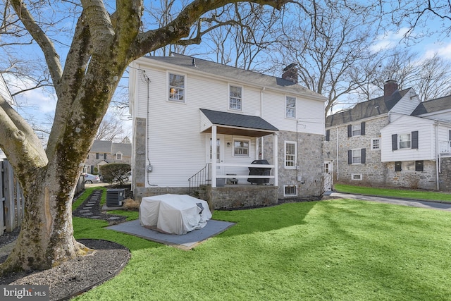 rear view of property with fence, a yard, a chimney, and central air condition unit