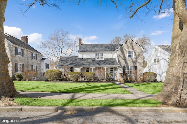 view of front of property featuring a porch, a chimney, and a front lawn