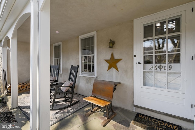 view of exterior entry featuring a porch and stucco siding