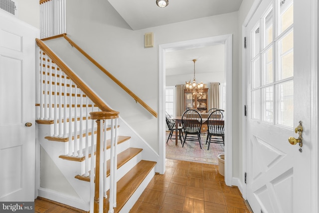 stairway featuring baseboards, a healthy amount of sunlight, visible vents, and a notable chandelier