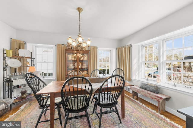 dining room featuring wood finished floors, baseboards, and an inviting chandelier