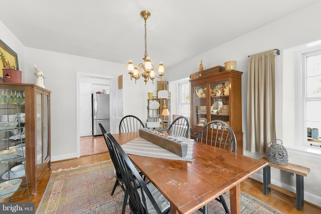 dining room featuring light wood-type flooring, an inviting chandelier, and baseboards