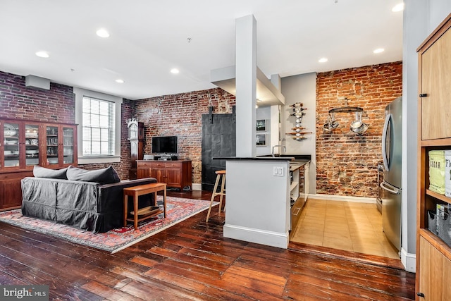 living room with recessed lighting, wood-type flooring, baseboards, and brick wall