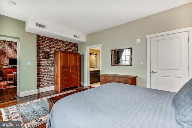 bedroom with brick wall, visible vents, baseboards, and wood finished floors