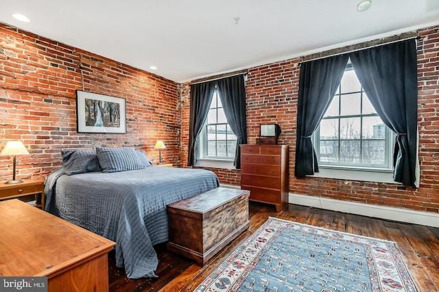 bedroom with wood-type flooring, baseboards, and brick wall