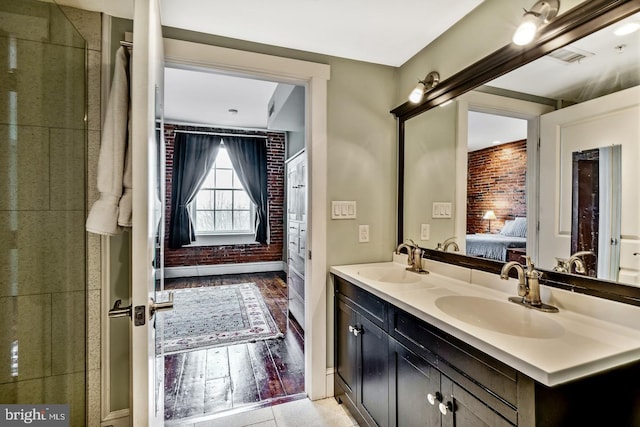 ensuite bathroom with brick wall, ensuite bath, and a sink