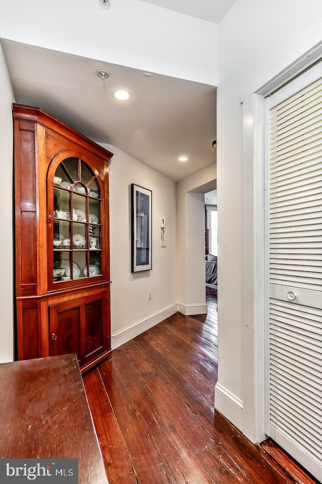 hall with dark wood-style floors, recessed lighting, and baseboards