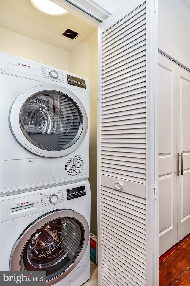 clothes washing area featuring visible vents, stacked washer and dryer, and laundry area