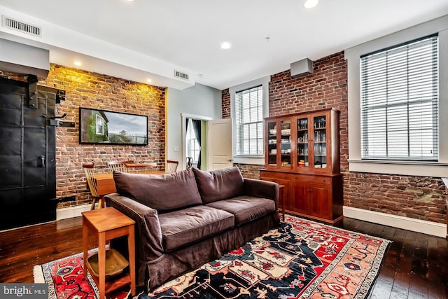 living area with brick wall, wood-type flooring, and visible vents