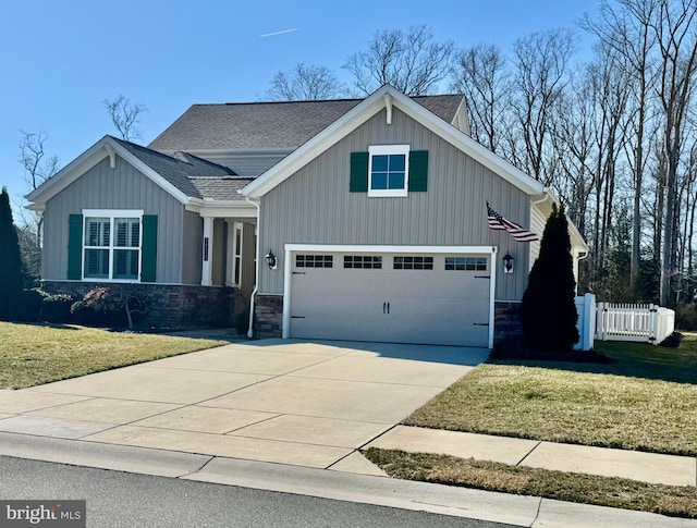 craftsman-style home featuring stone siding, fence, driveway, and a front lawn