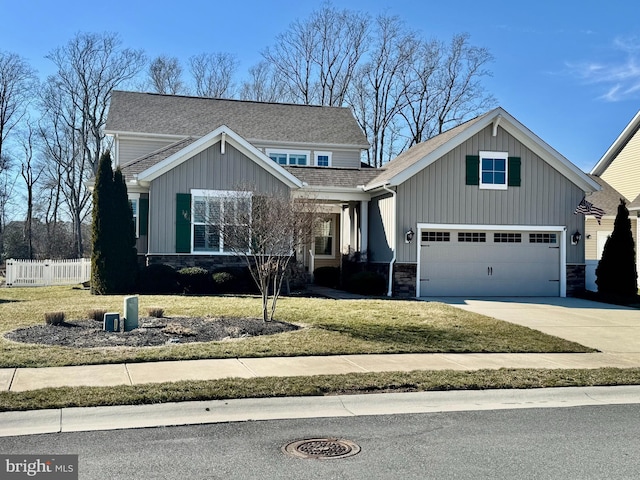 craftsman house featuring board and batten siding, a front yard, fence, stone siding, and driveway