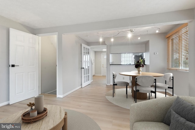 dining area with light wood-type flooring and baseboards