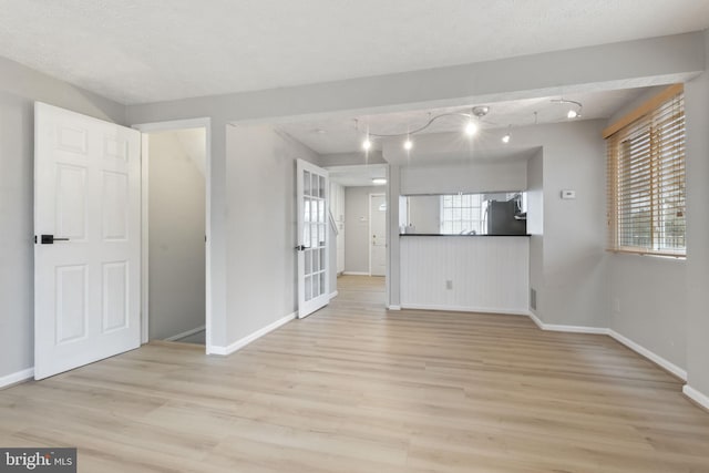 unfurnished living room featuring light wood finished floors and baseboards