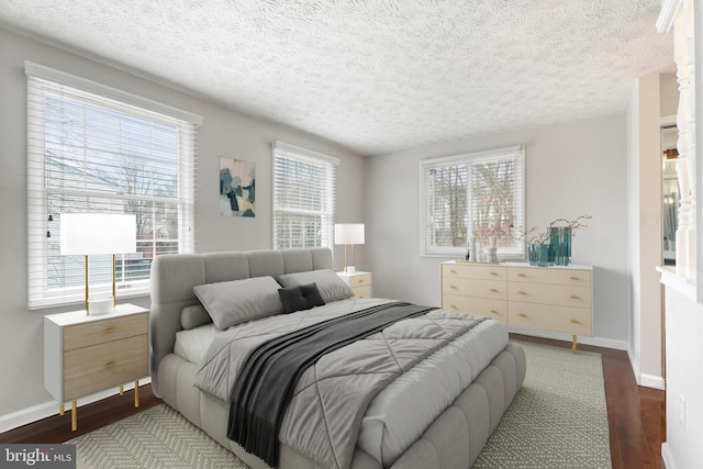 bedroom with a textured ceiling, baseboards, and wood finished floors