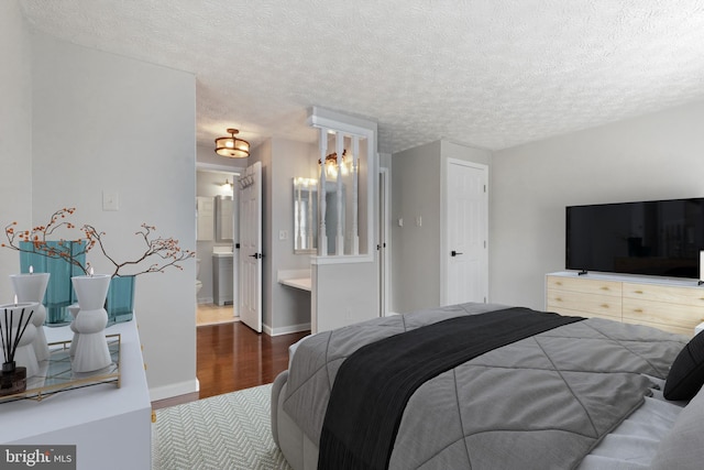 bedroom featuring connected bathroom, a textured ceiling, baseboards, and wood finished floors