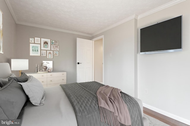 bedroom featuring baseboards, a textured ceiling, ornamental molding, and wood finished floors