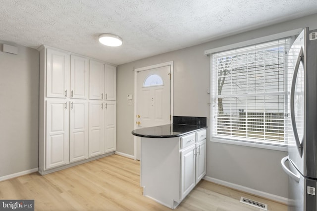 kitchen featuring freestanding refrigerator, plenty of natural light, visible vents, and white cabinetry