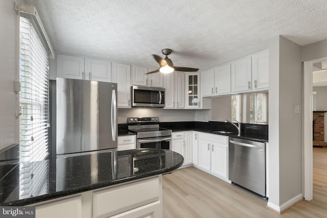 kitchen with stainless steel appliances, a healthy amount of sunlight, glass insert cabinets, and light wood finished floors