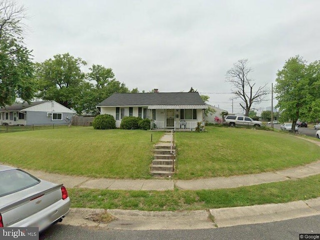 view of front of property with a front yard, covered porch, and fence