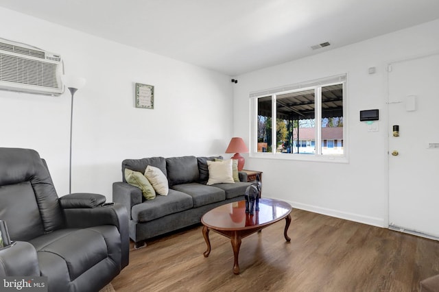 living room with baseboards, visible vents, wood finished floors, and a wall mounted air conditioner