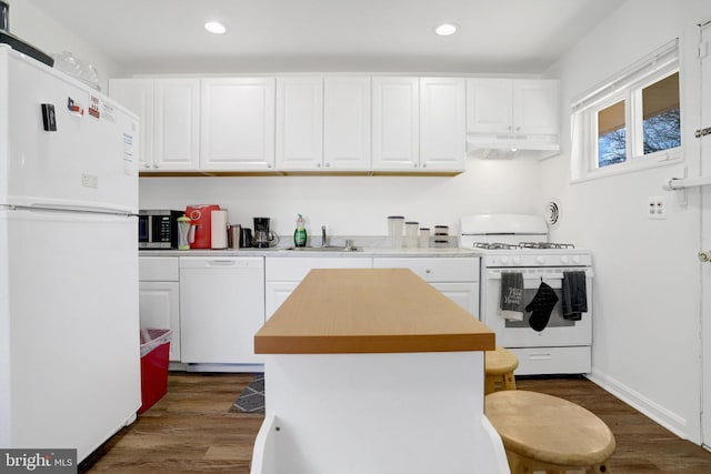 kitchen with under cabinet range hood, white appliances, dark wood-style flooring, a sink, and white cabinetry