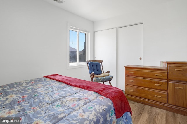 bedroom featuring a closet, wood finished floors, and visible vents