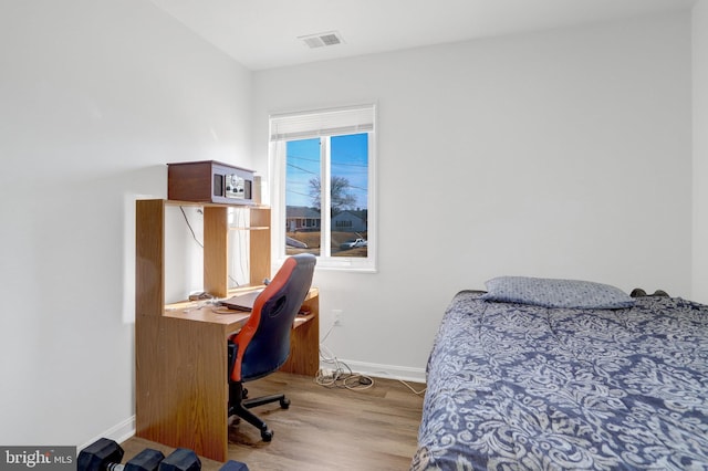 bedroom featuring visible vents, baseboards, and wood finished floors