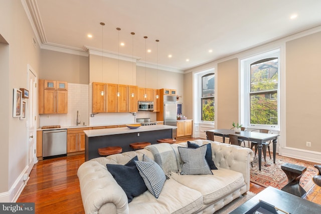 living room featuring baseboards, ornamental molding, wood finished floors, and recessed lighting