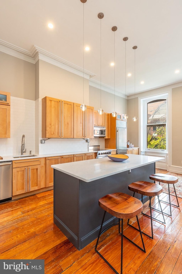 kitchen featuring hardwood / wood-style flooring, ornamental molding, stainless steel appliances, and a sink