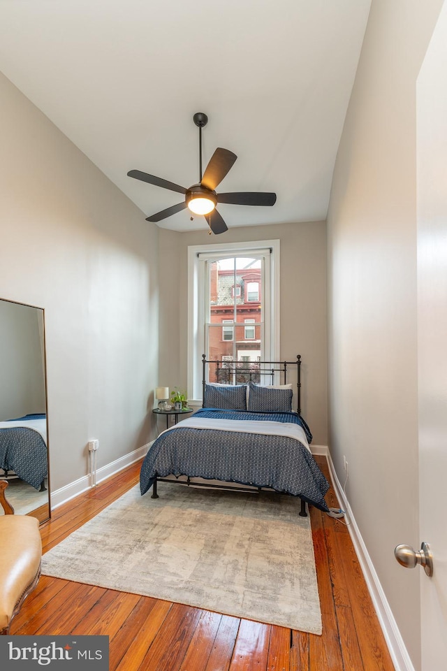 bedroom featuring hardwood / wood-style flooring, baseboards, vaulted ceiling, and a ceiling fan