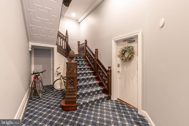 stairs featuring a towering ceiling, carpet, baseboards, and crown molding