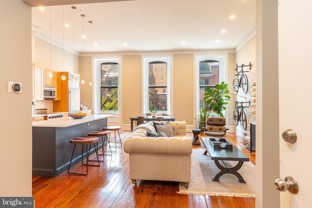 living room featuring ornamental molding, recessed lighting, wood-type flooring, and baseboards