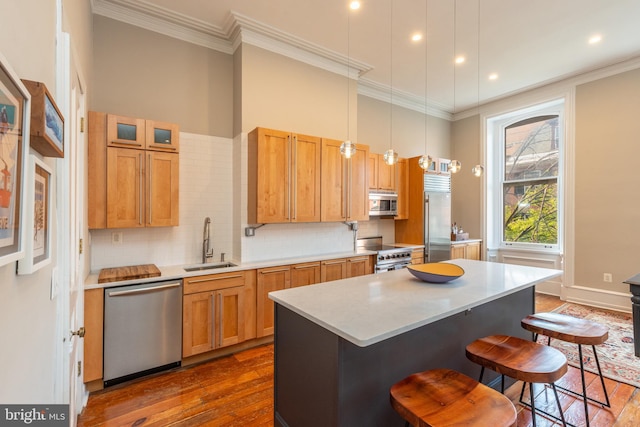 kitchen with dark wood-style floors, a breakfast bar, crown molding, high end appliances, and a sink