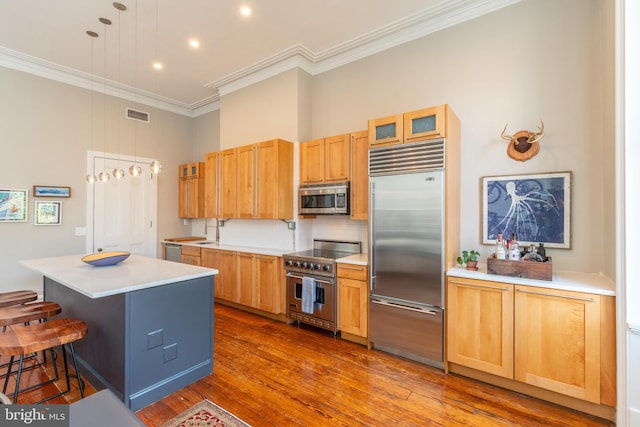 kitchen featuring a breakfast bar area, visible vents, a center island, high end appliances, and crown molding