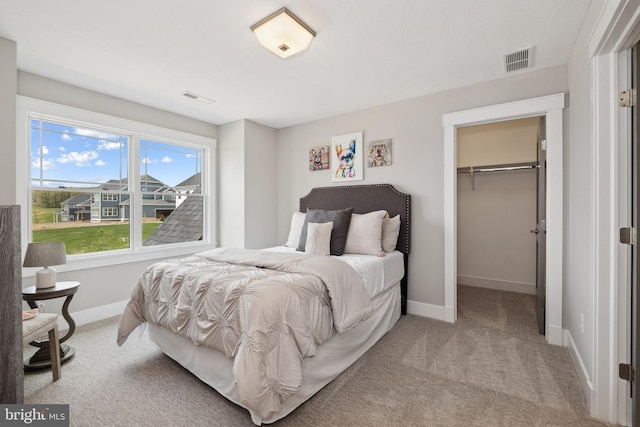 bedroom featuring a spacious closet, visible vents, and light colored carpet