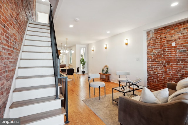 living room with baseboards, brick wall, stairway, and light wood-style floors