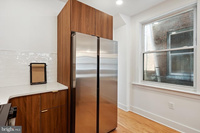 kitchen featuring modern cabinets, brown cabinets, freestanding refrigerator, light countertops, and light wood-type flooring