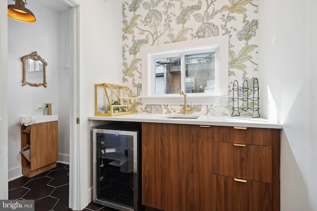 bar with wine cooler, dark tile patterned flooring, a sink, baseboards, and wallpapered walls